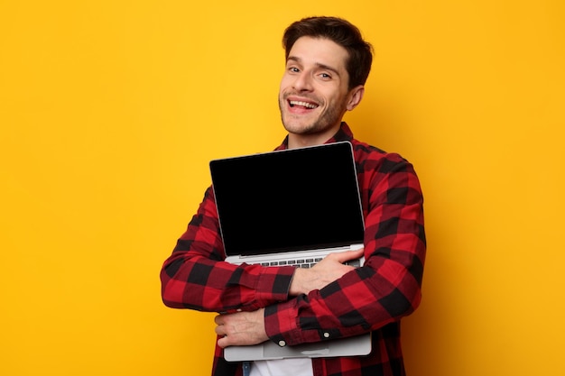 Gadget lover excited man hugging laptop at studio