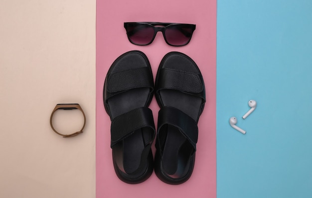 Photo gadgets and women's accessories on a colorful pastel background. sandals, smart bracelet, headphones, sunglasses. top view. flat lay