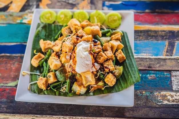 Gado-gado Indonesische salade geserveerd met pindasaus. Ingrediënten: tofu, spinazie, snijbonen, sojascheuten, aardappelen, komkommer en gekookte eieren