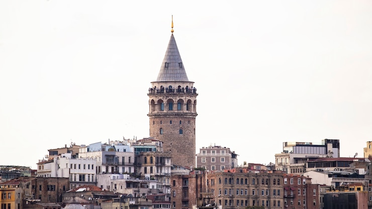 Photo galata tower with levels of residential buildings in front of it at cloudy weather istanbul, turkey