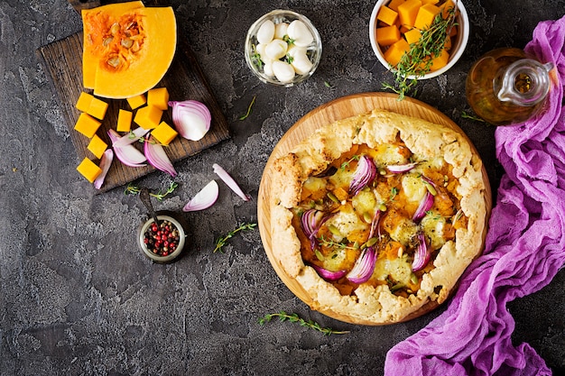 Galette pie with pumpkin and mozzarella cheese on dark background. Thanksgiving day food