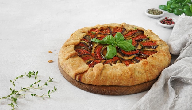 Galette ratatouille with eggplant zucchini tomato on gray background copy space