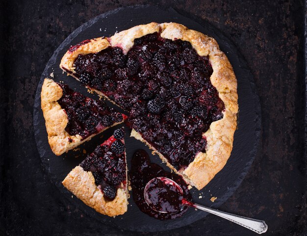 Photo galette with blackberries on a black background.