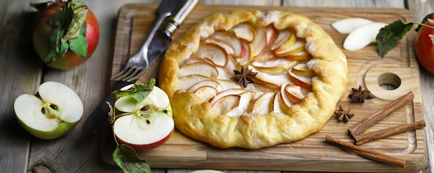 Galette with fresh apples on a wooden cutting board