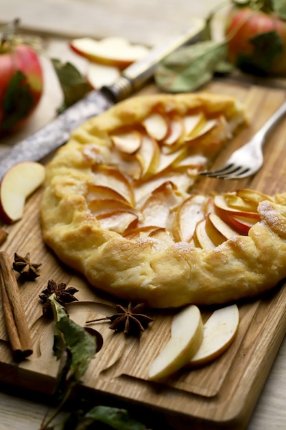 Galette with fresh apples on a wooden cutting board