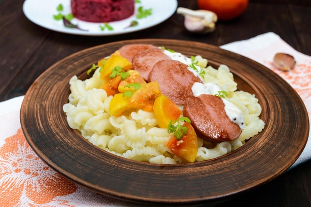 Foto galetti pasta met stukjes worst gele tomaten en romige mosterdsaus