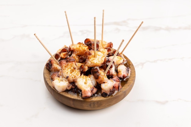 Galician style octopus in wooden plate on marble table. Typical appetizer of Galicia, Spain. Pulpo a Feira