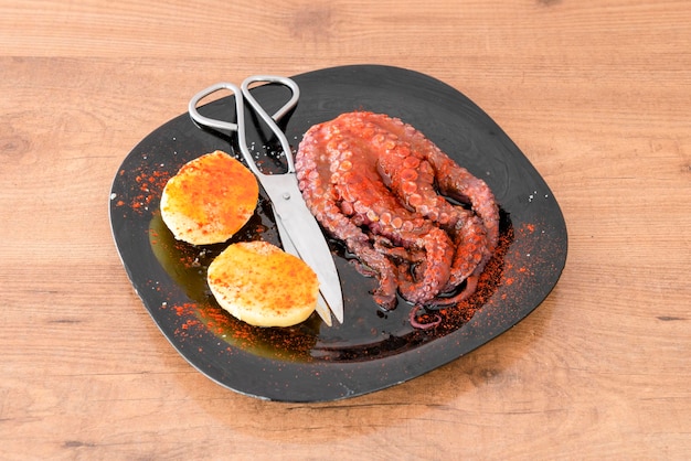 Galicische gekookte octopus met aardappelen olijfolie paprika van La Vera en zeezout met een visschaar om ze fijn te hakken