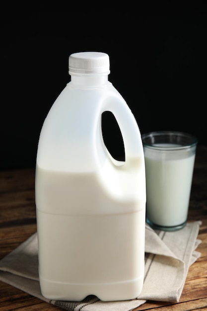 Gallon bottle and glass of milk on wooden table