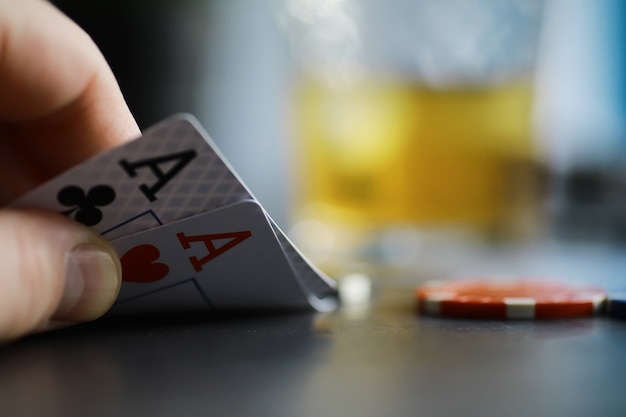 Giochi di carte per soldi. il poker in versione texas holdem. carte in mano, fiches da gioco, un mazzo di carte alcoliche in un bicchiere.