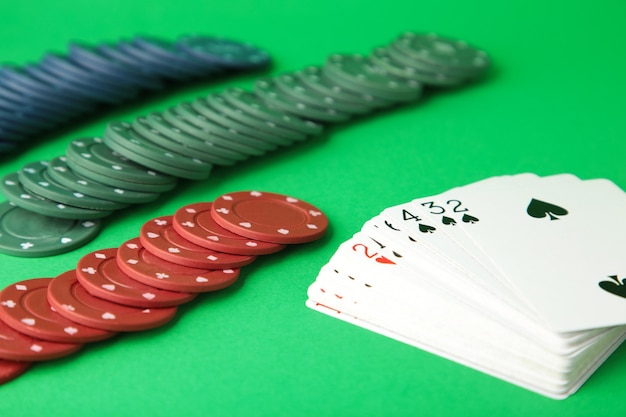 Gambling chips and card for poker on green wall. top view