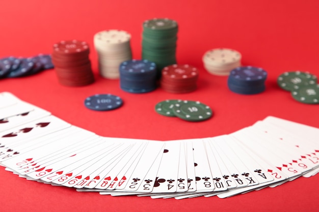 Foto chip di gioco e carte per il poker sulla parete rossa. vista dall'alto