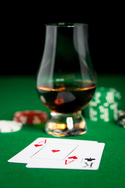 gambling, fortune and entertainment concept - close up of casino chips, whisky glass, playing cards and cigar on green table surface