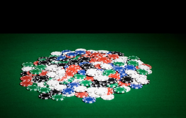 写真 ギャンブル、幸運、ゲーム、エンターテインメントのコンセプト-緑のテーブルの表面にカジノチップのクローズアップ