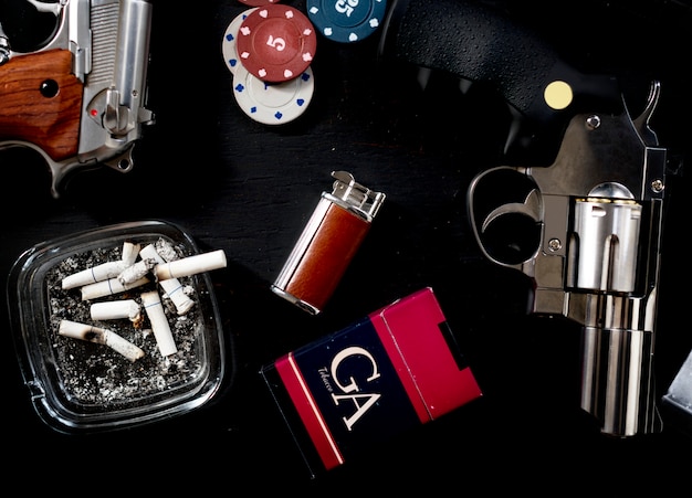 Gambling and gangster table set up with cigarettes and gun.