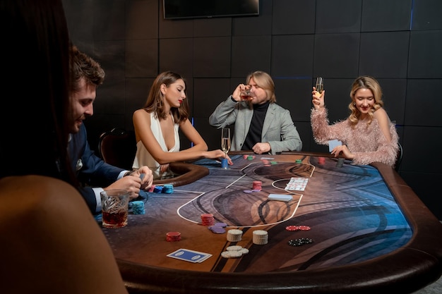 Photo gambling men and women playing poker at gaming table and drinking alcohol