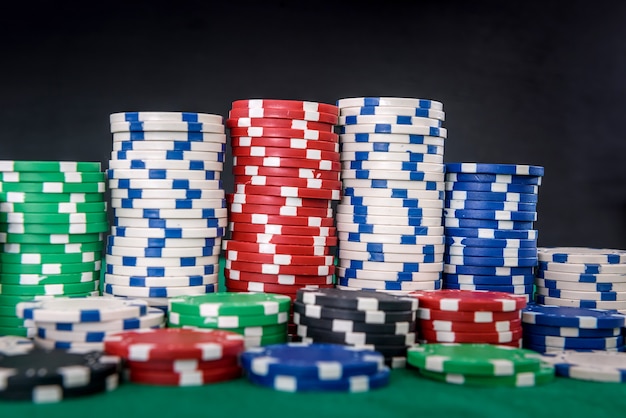 Gambling theme. Colorful playing chips in stacks on green table close up