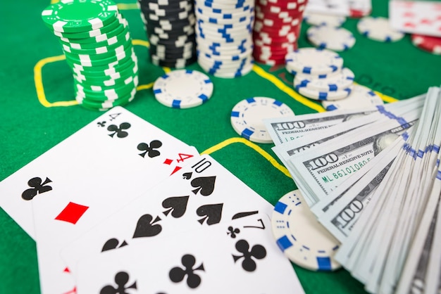 GamblingPoker game concept Poker cards with chips and dollars on a green poker table