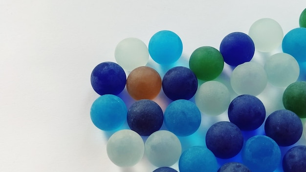 Игровые кликеры или цветные стеклянные шарики, разбросанные по белому фону с подсветкой