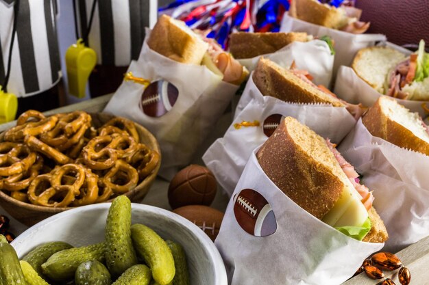 Game day football party table with  sub sandwich and snacks.