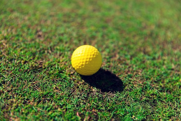 Photo game, entertainment, sport and leisure concept - close up of yellow golf ball on green field grass