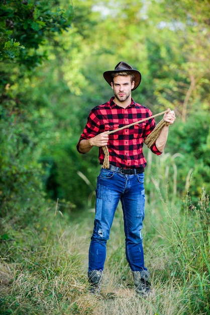 ゲームは、投げ縄ロープで帽子屋外カウボーイの野生の西ロデオ男牧場で西洋人チェッカーシャツヴィンテージスタイルの男野生の西レトロカウボーイ西部カウボーイの肖像画