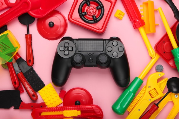 Gamepad and many children's toys on pink pastel