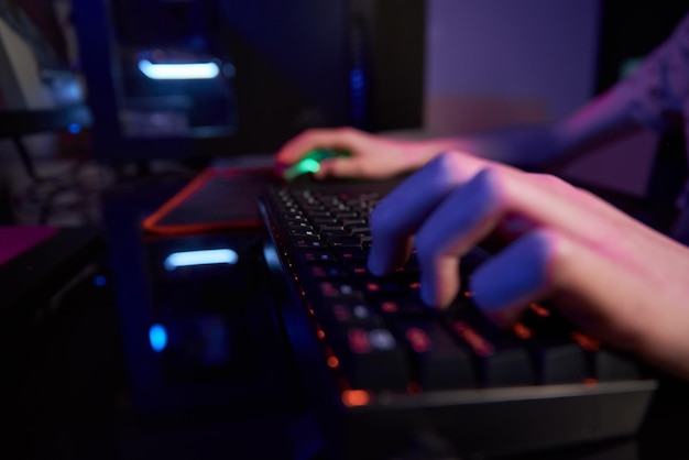 Gamer play computer game, use rgb neon colored keyboard