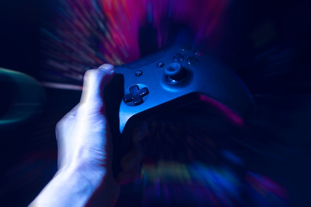 Gamer playing the online game with joystick controller in neon glow dark cyberpunk room gaming and esports challenge tournament streaming streamer with analog device in living house