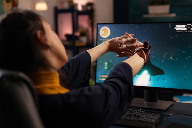 Gamer preparing to play online video games on computer. Woman using keyboard and mousepad, playing digital game on monitor at desk. Player gaming in cyberspace, having fun with games.