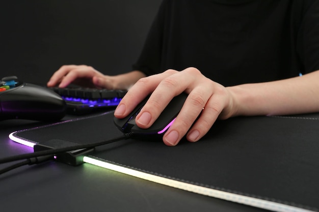 暗いテーブルのクローズアップで現代的な有線コンピュータマウスを使用するゲーマー