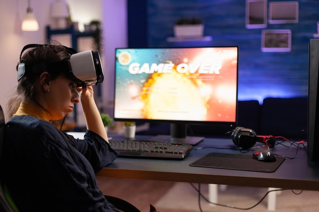 게이머는 vr 고글을 사용하여 비디오 게임을 하고 컴퓨터에서 지고 있습니다. 모니터와 가상 현실 안경의 컨트롤러로 온라인 게임을 하는 사람. 게임 장비를 가진 성인.