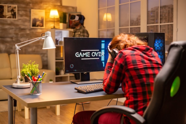 Gamer-vrouw verliest bij een videogame die 's avonds laat in de woonkamer speelt.