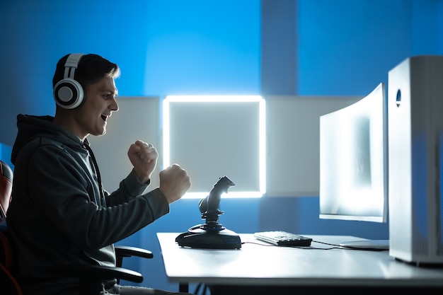 The gamer with headphones playing video games on the illuminated background