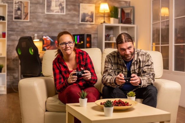 Coppia di giocatori che giocano ai videogiochi sulla tv con controller wireless in mano.