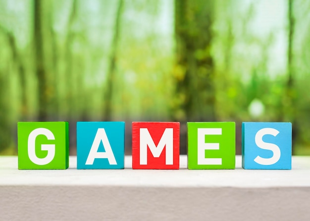 緑の自然の背景に木製のカラフルなブロックに書かれたゲームの単語