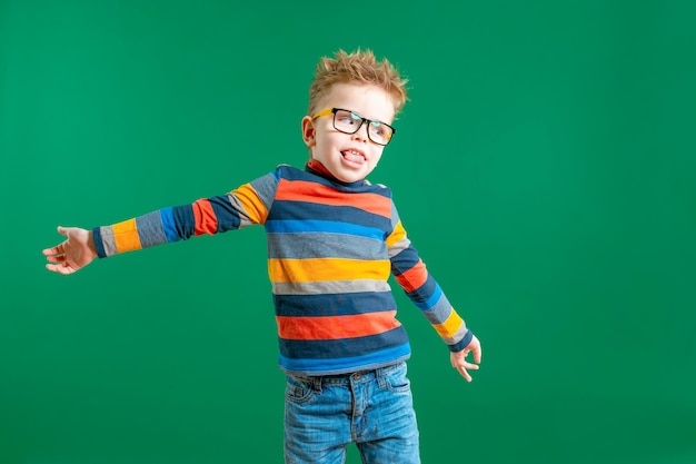 Gamine boy in glasses on a green background in the studio Closeup