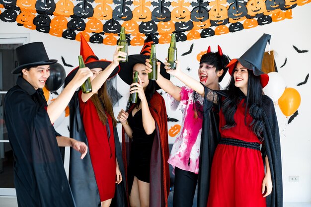 Gang of young Asian in costume witch, wizard with celebrate Halloween party for dance and drink and drunk in the room. Group teen Thai with celebrate Halloween. Concept party Halloween at home.