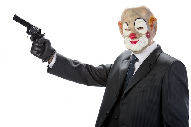 Foto gangster mascherato da clown con una pistola durante una rapina.