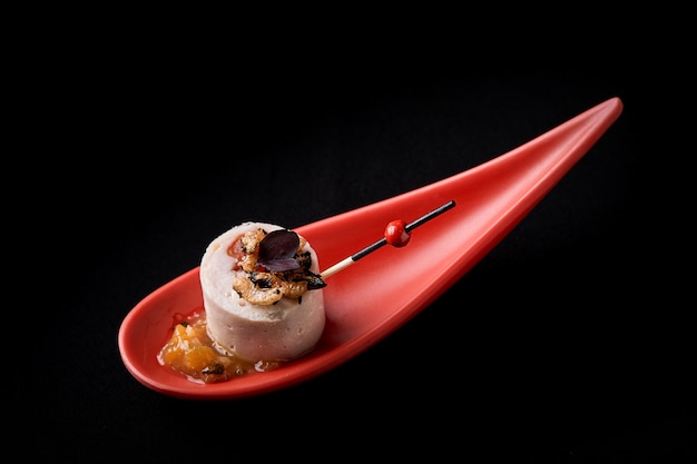 Ganzenleverpastei, foie gras, geserveerd op zwarte steen in Japanse rode lepels.