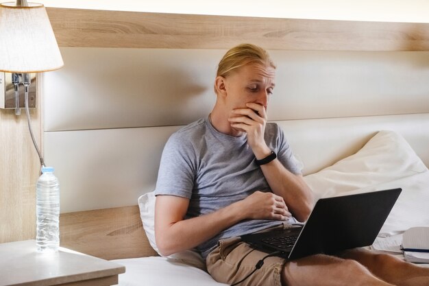 Gapende freelancer werkt online aan hotelbed