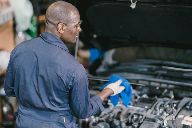 Garage Mechanic African Black male professional working car auto service checking engine oil