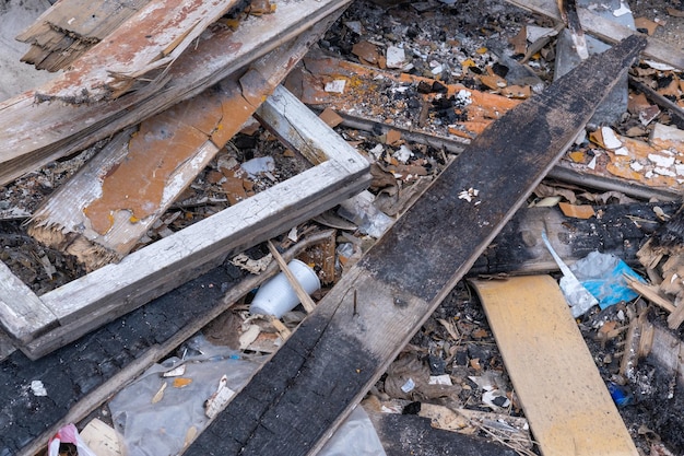 Garbage background from old burnt wooden boards bricks plastic Garbage after the destruction of the house Waste recycling