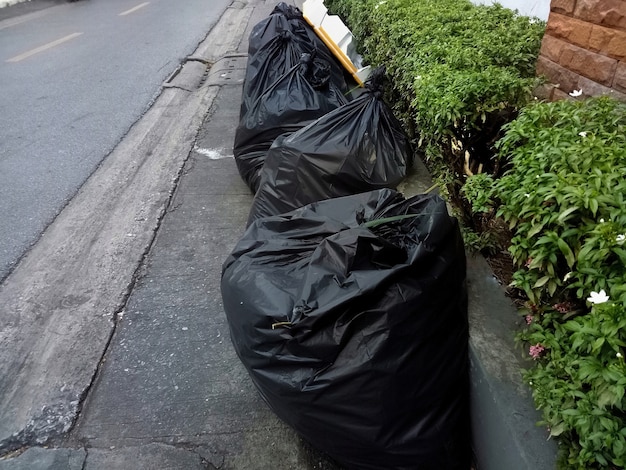 Garbage bags, black bin bags, on the foot path. environment and
object concept.