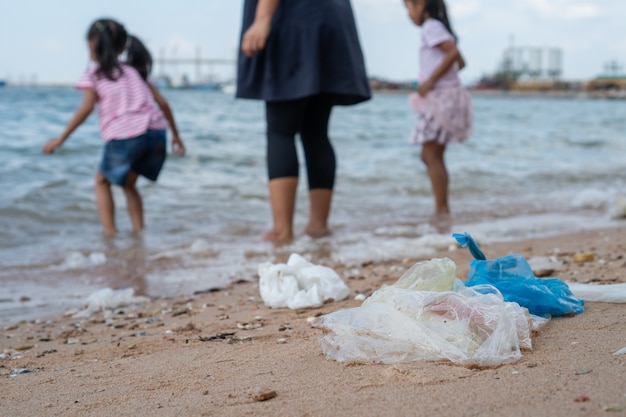 Garbage on the beach with family playing water in the sea on background