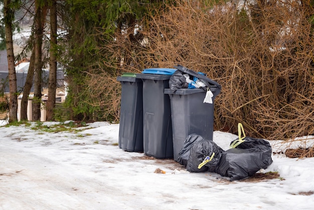 겨울에 주거 지역의 하얀 눈 위에 쓰레기로 가득 찬 쓰레기통.