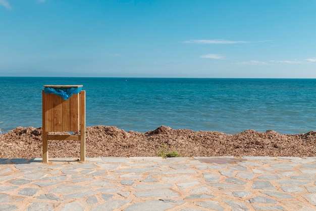 Foto pattumiera in piedi in riva al mare sullo sfondo di un bel cielo e di un paesaggio marino seaside