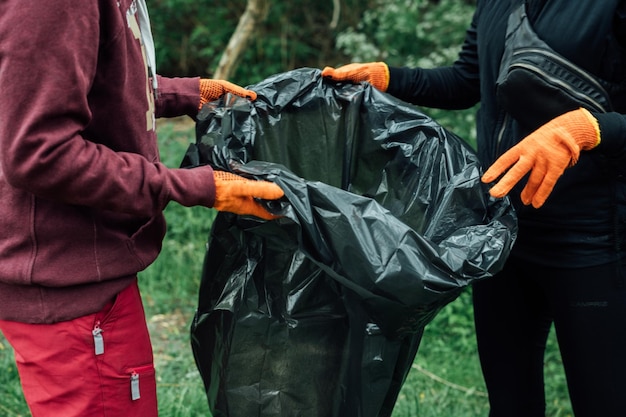 Garbage collection in nature black garbage bag and hands