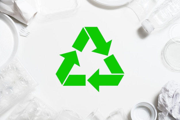 Garbage recycling. Environmental protection. Plastic tableware arranged around green symbol.