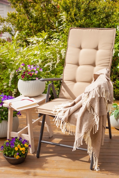 Garden chair on terrace in sunlight, pansy flowers